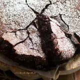 Torta al cioccolato fondente, con una crosta screpolata e cosparsa di zucchero a velo, pronta per essere gustata.