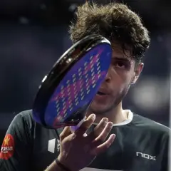 Giocatore di padel con racchetta in primo piano, concentrato. Un punto d'oro per il padel.