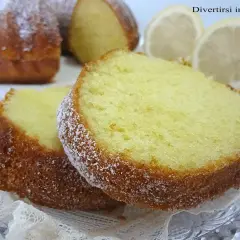 Fette di ciambellone al limone spolverate di zucchero a velo, con spicchi di limone sullo sfondo.