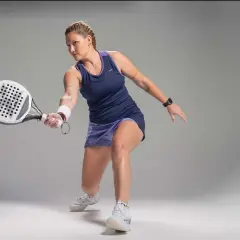 Giocatrice di padel in azione, con racchetta in mano, pronta a colpire la palla. La sua concentrazione è palpabile, un vero esempio di passione per il **padel**.