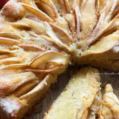 Una deliziosa torta di mele senza zucchero, con fette di mela disposte a raggiera sulla superficie dorata e una spolverata di zucchero a velo.