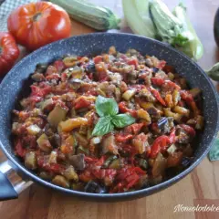 Ratatouille ricetta in padella, con melanzane, zucchine, pomodori e peperoni, guarnito con basilico fresco.