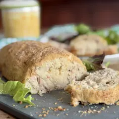 Polpettone di tonno dorato e croccante, tagliato a fette, servito con insalata fresca.