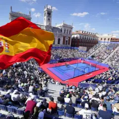 Bandiera spagnola sventola su un campo da padel gremito di spettatori. Atmosfera vibrante per il padel in Spagna.