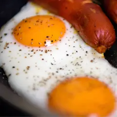 Due uova occhio di bue con pepe nero e salsicce in padella.