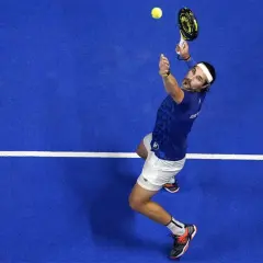Giocatore di padel in azione, pronto a eseguire uno smash x3. La palla è in aria, la racchetta alza.