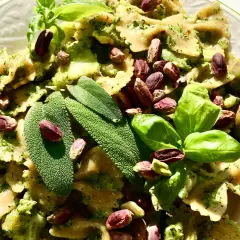 Farfalle condite con un saporito pesto di salvia, guarnite con pistacchi, basilico e olive verdi.