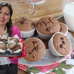 Donna sorridente presenta una teglia di muffin al cioccolato senza burro, perfetti per una colazione golosa.