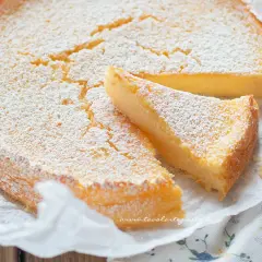 Deliziosa torta ricotta e limone, cosparsa di zucchero a velo, con una fetta tagliata.