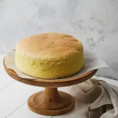 Una soffice torta con albumi, dorata e leggera, su un alzata di legno. Perfetta per una colazione o merenda.