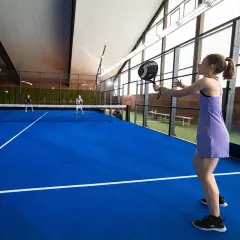 Ragazza in campo da padel 1 vs 1, pronta a colpire la palla.