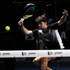 Giovane giocatore di padel colpisce la palla con un potente top spin, concentrato sul gioco.