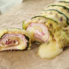 Delizioso rotolo di zucchine con prosciutto e formaggio filante, una ricetta gustosa e leggera.
