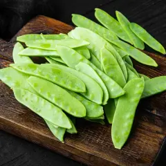 Taccole fresche su tagliere di legno, pronte per gustose ricette primaverili.