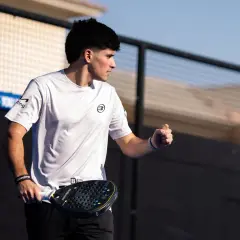 Maxi Sanchez, concentrato, con racchetta da padel in mano, esulta sul campo.