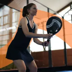 Donna gioca a padel, concentrata sul colpo. Impara i trucchi padel principianti per migliorare il tuo gioco.