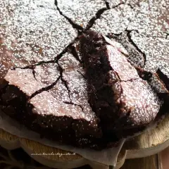 Torta al cioccolato fondente, con una crosta screpolata e cosparsa di zucchero a velo, pronta per essere gustata.