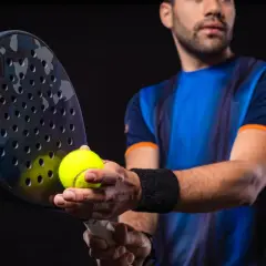 Giocatore di padel con racchetta e pallina, pronto a migliorare il suo gioco.