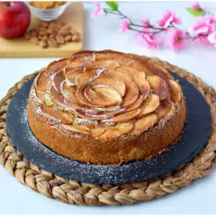 Deliziosa torta di mele vegana, decorata con fettine di mela disposte a spirale e spolverata di zucchero a velo.