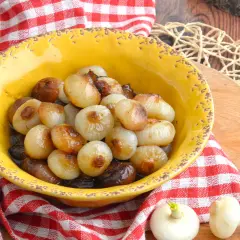 Cipolline caramellate in agrodolce, servite in una ciotola gialla con tovagliolo a quadri rossi.