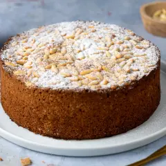 Torta soffice con farina di mandorle, cosparsa di pinoli e zucchero a velo.