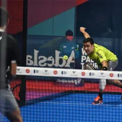 Giocatore di padel in maglia verde colpisce la palla, con un avversario di spalle. Il **chiquita significato** in questo sport è un colpo basso e angolato.