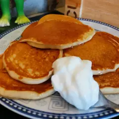 Pancake senza uova con yogurt, una pila dorata su un piatto decorato, pronta per essere gustata.