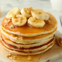Pancake light con banane e noci, inzuppati nello sciroppo d'acero. Un piacere per gli occhi e per il palato.