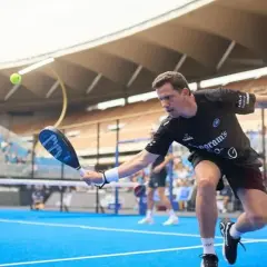 Paquito Navarro in azione, colpisce la palla con la racchetta da padel su un campo blu, con il pubblico sugli spalti.