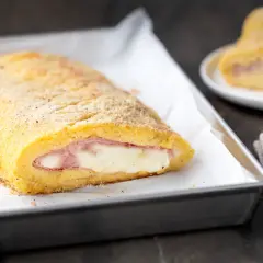 Polpettone di patate ripieno di prosciutto e formaggio filante, dorato e croccante, pronto per essere gustato.