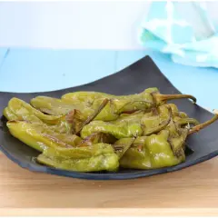 Friggitelli al forno, verdi e succosi, serviti su un piatto nero. Un contorno semplice e gustoso.