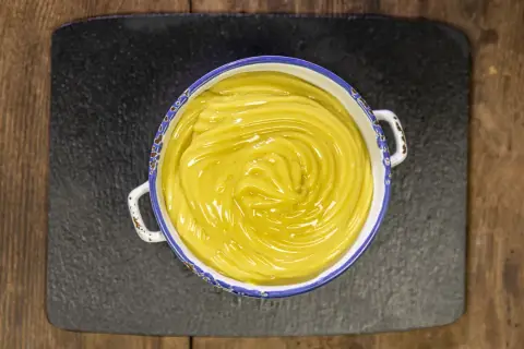 Crema pasticcera vegana, liscia e lucida, in una ciotola con bordo decorato, pronta per farcire dolci.