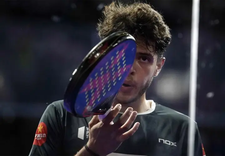 Giocatore di padel con racchetta in primo piano, concentrato. Un punto d'oro per il padel.