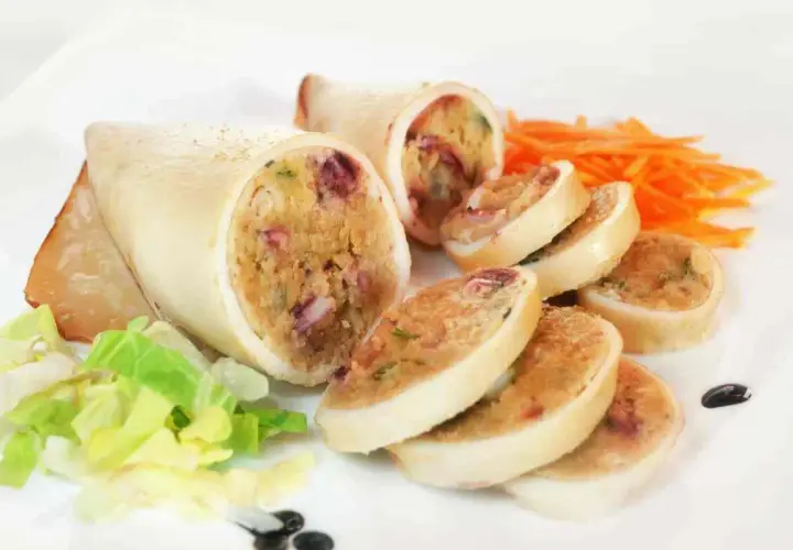Seppie ripiene, un piatto gustoso con un ripieno ricco e colorato, servite con insalata fresca e carote julienne.