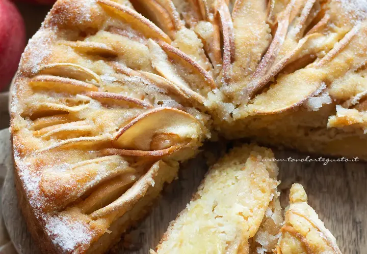 Una deliziosa torta di mele senza zucchero, con fette di mela disposte a raggiera sulla superficie dorata e una spolverata di zucchero a velo.