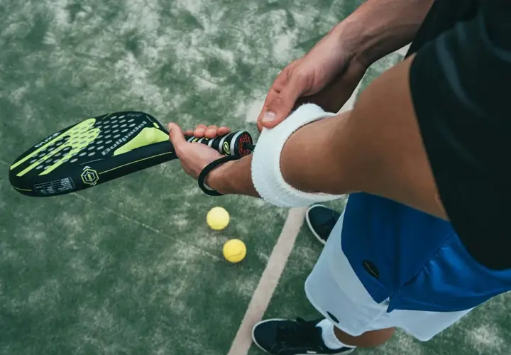 Un giocatore si prepara per una partita di padel negli Stati Uniti, impugnando la racchetta e con le palline a portata di mano.