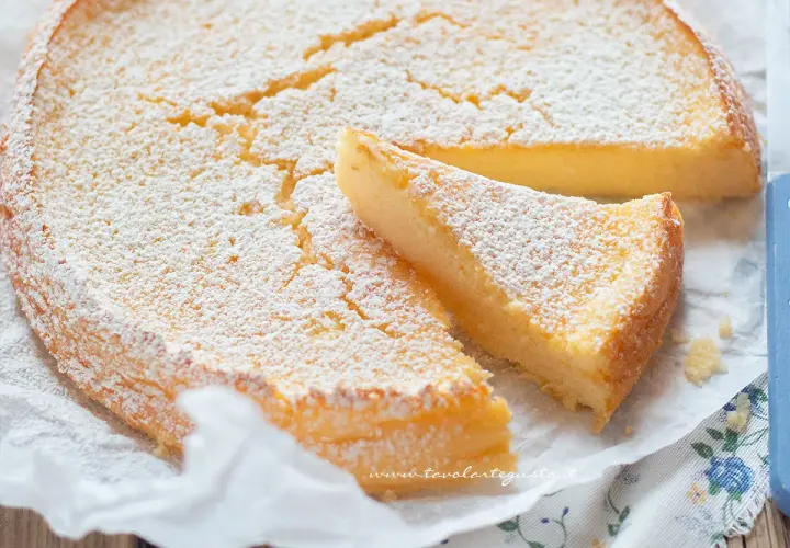 Deliziosa torta ricotta e limone, cosparsa di zucchero a velo, con una fetta tagliata.
