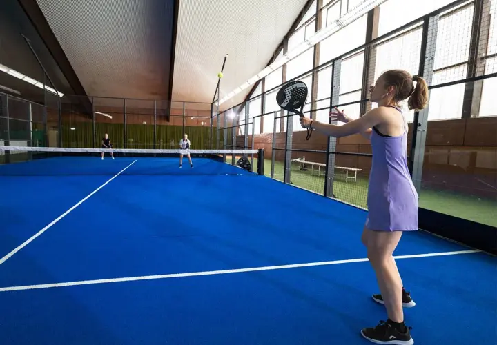Ragazza in campo da padel 1 vs 1, pronta a colpire la palla.