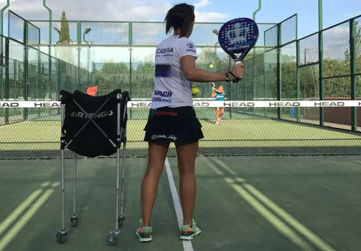 Allenamento intensivo per il corso istruttore padel. Una giocatrice si prepara a colpire la palla su un campo da padel.
