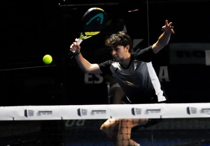 Giovane giocatore di padel colpisce la palla con un potente top spin, concentrato sul gioco.