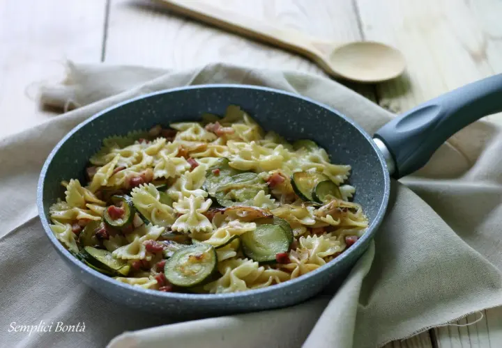 Farfalle con zucchine e pancetta croccante, un piatto semplice e gustoso pronto in padella.