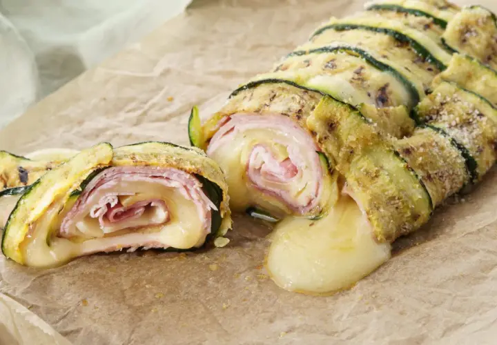 Delizioso rotolo di zucchine con prosciutto e formaggio filante, una ricetta gustosa e leggera.