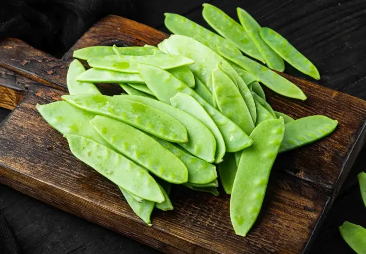 Taccole fresche su tagliere di legno, pronte per gustose ricette primaverili.