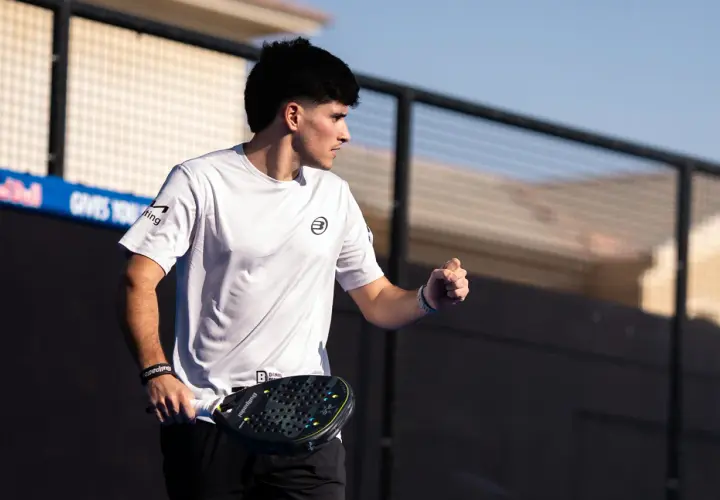 Maxi Sanchez, concentrato, con racchetta da padel in mano, esulta sul campo.