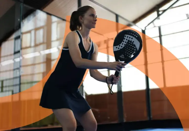 Donna gioca a padel, concentrata sul colpo. Impara i trucchi padel principianti per migliorare il tuo gioco.