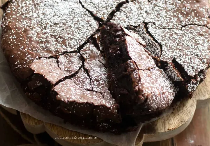 Torta al cioccolato fondente, con una crosta screpolata e cosparsa di zucchero a velo, pronta per essere gustata.