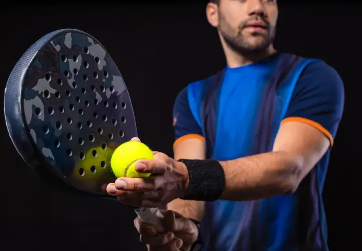 Giocatore di padel con racchetta e pallina, pronto a migliorare il suo gioco.