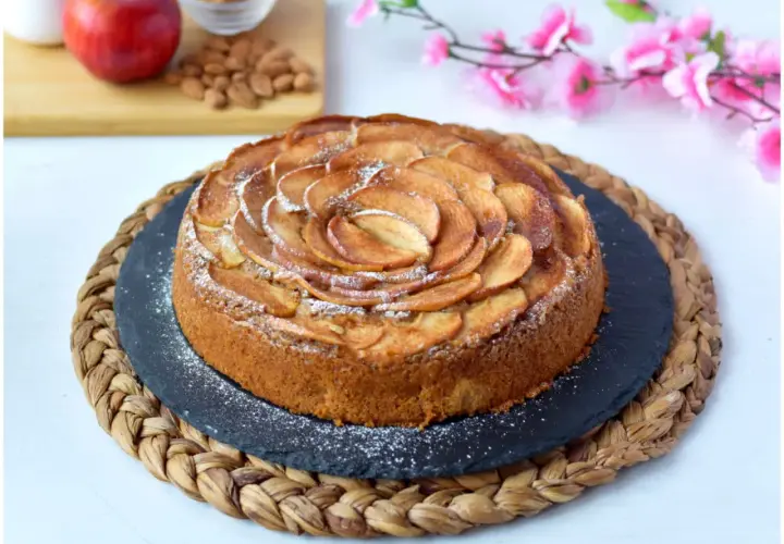 Deliziosa torta di mele vegana, decorata con fettine di mela disposte a spirale e spolverata di zucchero a velo.