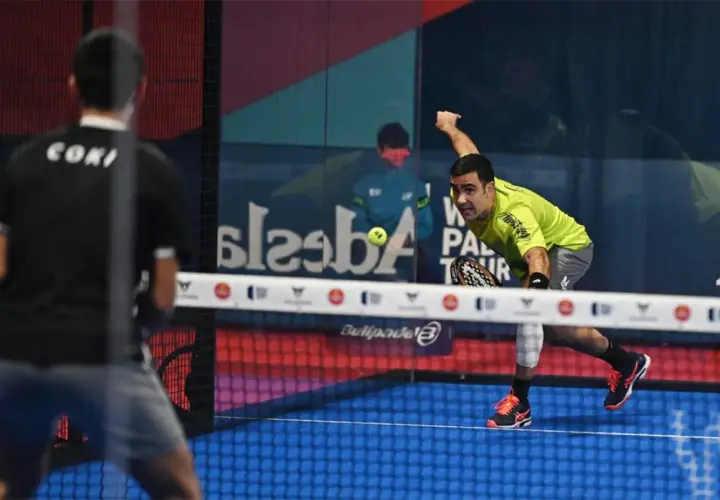 Giocatore di padel in maglia verde colpisce la palla, con un avversario di spalle. Il **chiquita significato** in questo sport è un colpo basso e angolato.