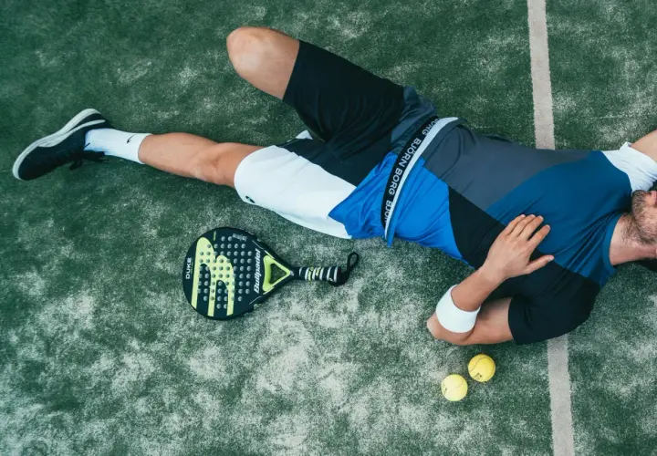 Giocatore di padel esausto, con racchetta e palline accanto. Forse ha appena eseguito un potente head smash.